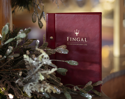 A red menu cover from Fingal Hotel's Lighthouse Restaurant & Bar with some Christmas decorations.