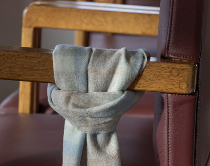 A tartan scarf tied to the arm of a chair.