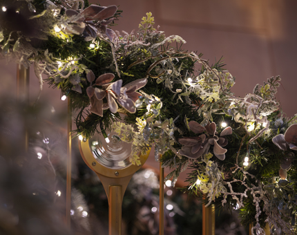 A close-up of a staircase with Christmas decorations wrapped around the handrails. 