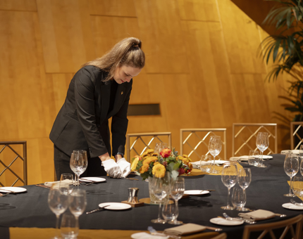 A member of the Hospitality team setting tables in the Ballroom.
