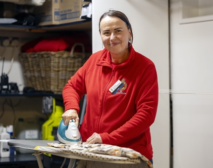 A member of the Housekeeping team ironing a curtain.
