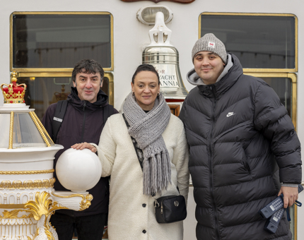 Three people posing for a photo at Britannia's Bell and binnacle. 