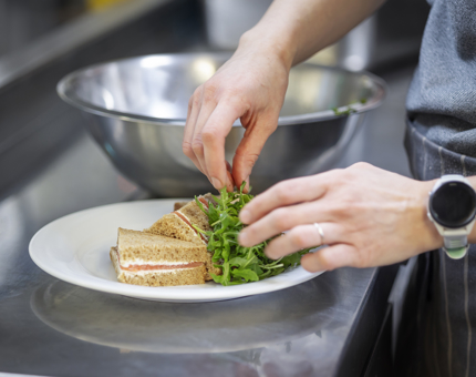 A Chef in the Galley preparing a smoked salmon sandwich. 