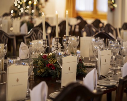 The State Dining Room with tables set. There is a lit candelabra and Christmas decorations. 