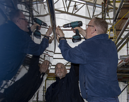 Two men from the Maintenance team are applying a rubbing strip on Bloodhound.