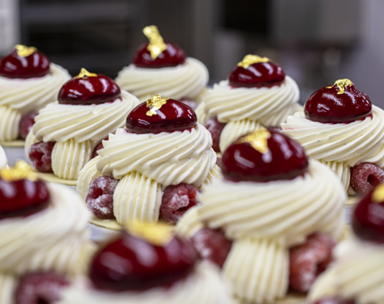 A tray containing raspberry and cream desserts. 
