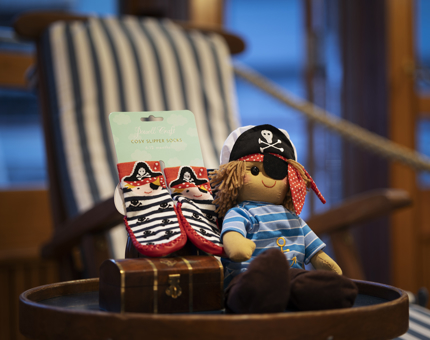 A pirate soft toy and a pair of kids sicks with pirates on them. 