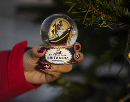 A hand holding a Britannia snow globe. 