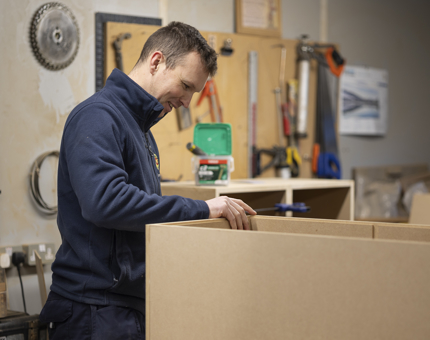 A Maintenance team member making a shelving unit. 