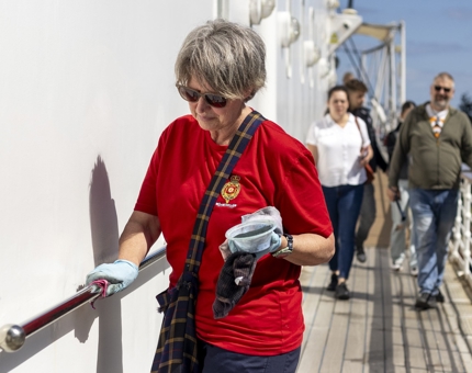 A Housekeeper polishing a handrail. 