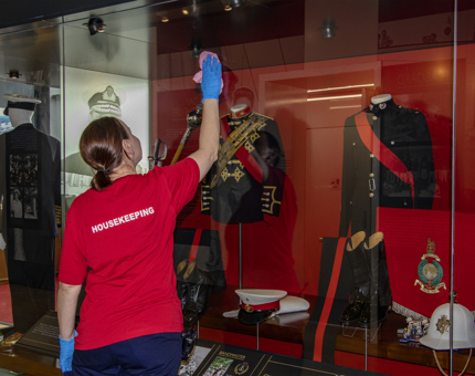 A Housekeeper dusting a display case. 