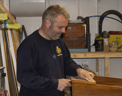 A man from the Maintenance Team is sanding the Chart Table. 