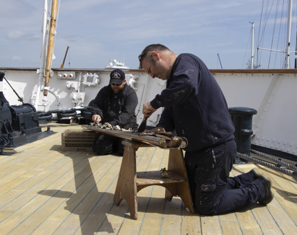 Two men strip handrails. 