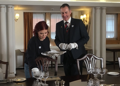 A man and woman in the State Dining Room setting a table.