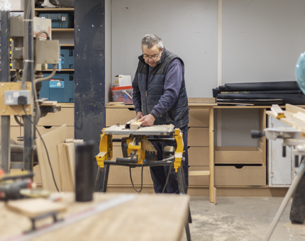 A Maintenance team member cutting molding for new office storage. 