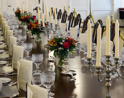 The dining table in the State Dining Room is set for an evening event with menus, candles and floral arrangements. 