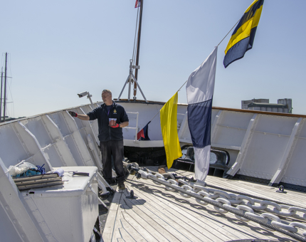 A member of the Maintenance Team is painting outside on deck. 