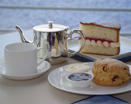 A slice of cake, scone and pot of tea in the Royal Deck Tearoom. 