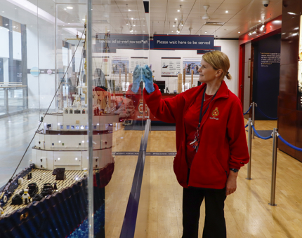 A woman from Housekeeping polishing the LEGO model case. 