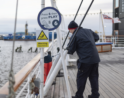 A Facilities Officer cleans the deck. 