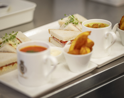 Two plates with a mugs of soup, wedges and sandwiches. 