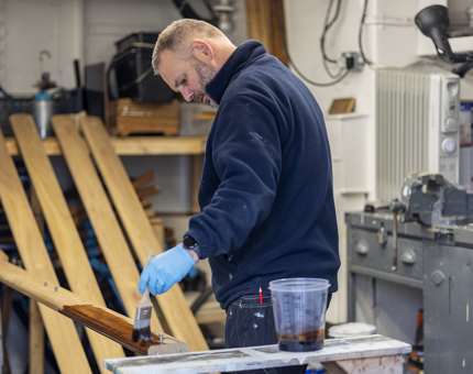 A Maintenance team member varnishing a handrail.