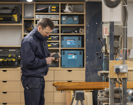 A maintenance team member filing the edges of a brass end before fitting it to a handrail. 