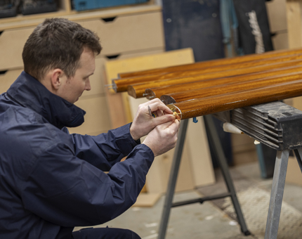 A brass end being fitted to a handrail by a Maintenance team member. 