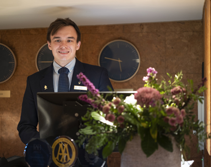 A Guest Services Assistant stands behind the reception desk at Fingal Hotel's entrance. 