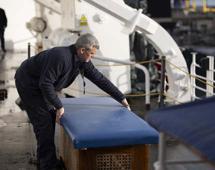 A maintenance team member replacing the top back on a bench on the tour route. 