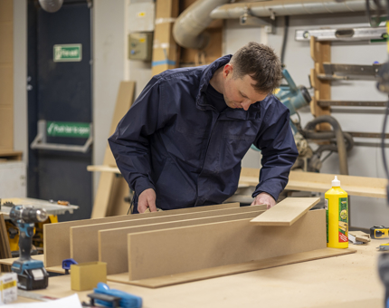A Maintenance team member assembling pigeon hole storage for the Yacht's drawings.