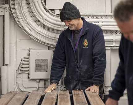 Two men sanding wooden handrails.