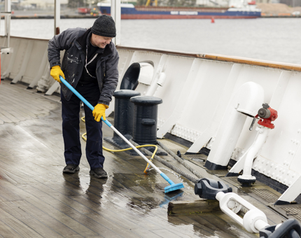 A man holding a brush cleaning the deck. 
