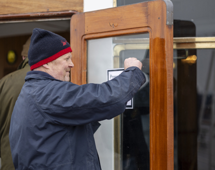 A Facilities Officer polishing the glass of a door. 