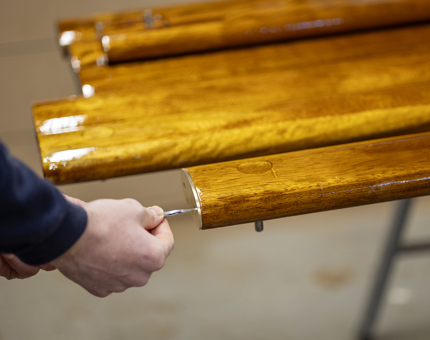 A close up of hands holding a screwdriver, fitting brass ends onto handrails.