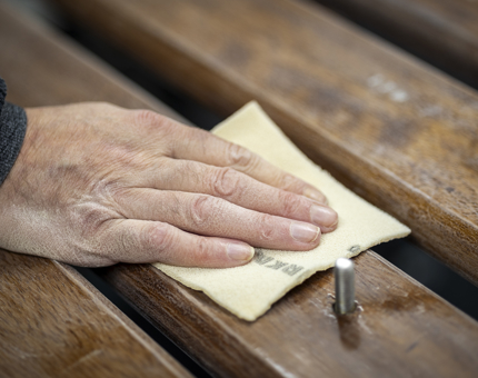 A close up of a hand sanding handrails.