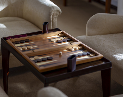 A board game on a table next to two cream sofa chairs. 