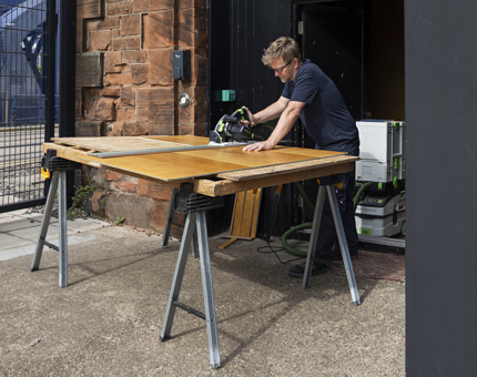 Outside Fingal Hotel, wood is being cut by a Maintenance man for porthole surrounds. 