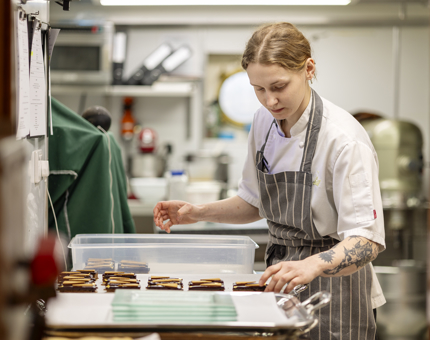 A chef placing cakes on a tray. 