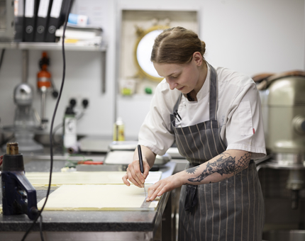 A chef in the Galley preparing a slab of white chocolate to make decorations. 