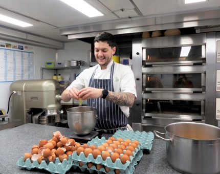 In the Pastry Galley, Bob, Junior Sous Chef, cracks some eggs.