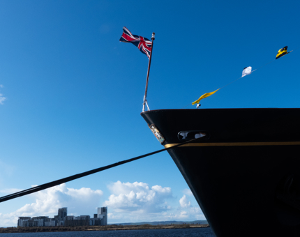 The dress flags fly in the wind above Britannia’s bow on a beautiful day in Leith.