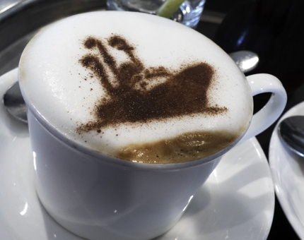 A foam topped cappuccino with a chocolate Britannia stencil on top. 