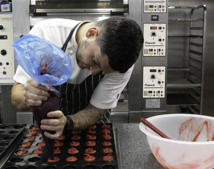 A Pastry Chef filling moulds with sorbet in the Galley. 