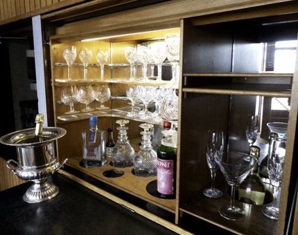 A drinks cabinet with doors showing illustrations of former Royal Yachts. 