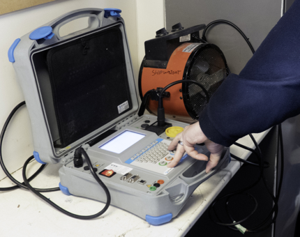 A member of the Maintenance team is using PAT testing equipment.