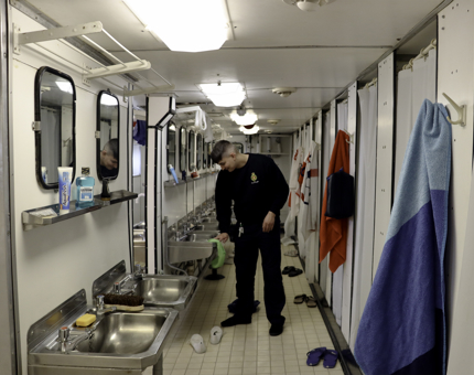Maintenance team member mops shower floors. 