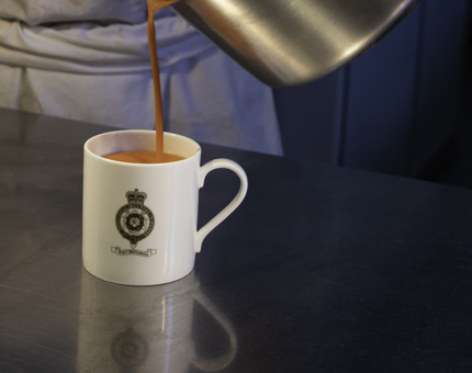 Tomato soup is poured into a Britannia mug. 