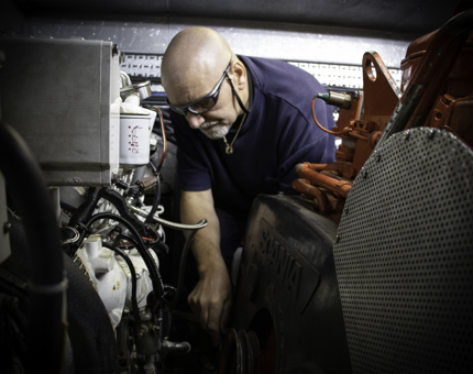 Man works on fixing a ship's pump amid machinery.