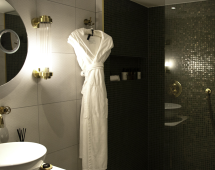 Inside Fingal cabin bathroom with white bathrobe and mosaic tiled shower. 